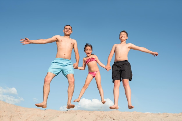 Vater mit spielenden Kindern am Sandstrand Familienspiele im Urlaub Lifestyle Freizeitsport