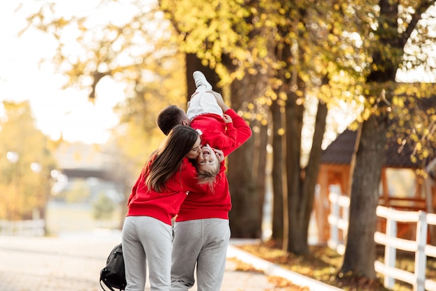 Vater, Mutter und kleine Tochter gehen im Herbstpark spazieren, glückliche Familie hat Spaß im Freien.