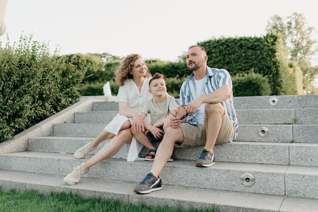 Vater, Mutter und Sohn sitzen auf den Stufen im Garten einer Altstadt