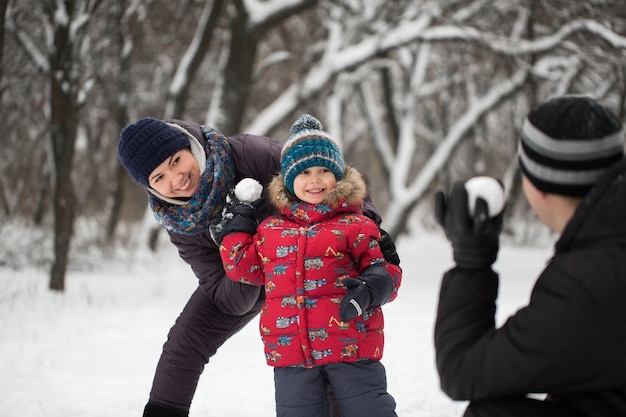 Vater, Mutter und Sohn spielen im Winter mit Schneebällen