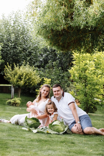 Vater, Mutter und zwei Kinder, Baby und kleine Tochter im Gras mit Kohl