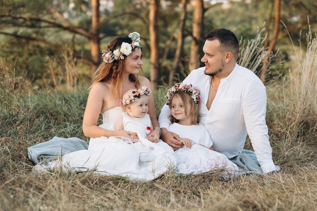 Vater, Mutter und zwei Kinder Töchter sitzen im Gras, verbringen Zeit und spielen in der Natur