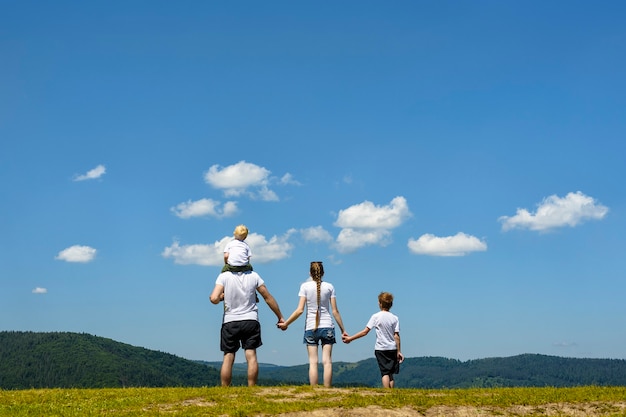 Vater, Mutter und zwei kleine Söhne stehen auf einer grünen Wiese im Hintergrund