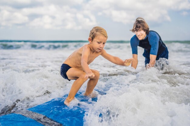 Vater oder Lehrer, der seinem 4-jährigen Sohn im Urlaub oder Urlaub das Surfen im Meer beibringt. Reisen und Sport mit Kinderkonzept. Surfkurs für Kinder