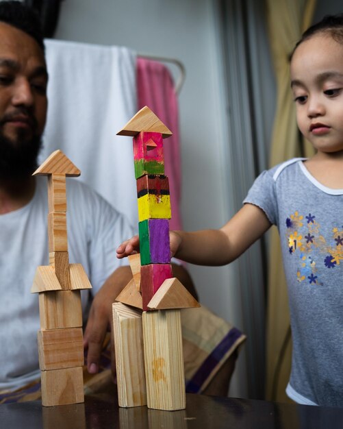 Foto vater schaut mädchen an, das mit spielzeugblöcken spielt