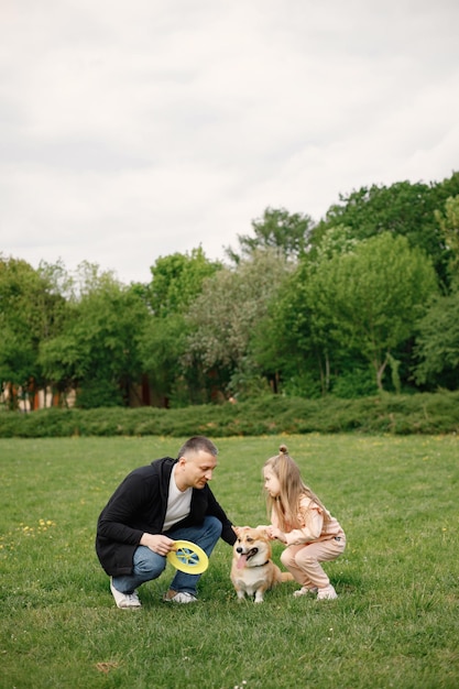 Vater seine Tochter und ihren Corgi-Hund beim gemeinsamen Spielen in einem Frühlingspark