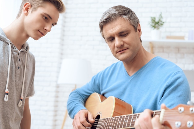 Vater spielt Gitarre und sein Sohn