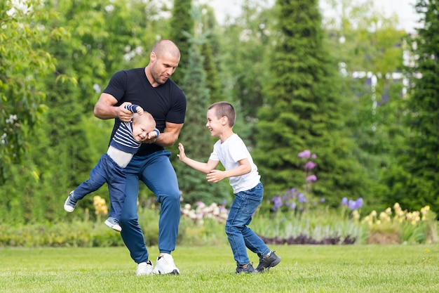 Vater spielt mit kleinen Jungen Sohn, umarmen Baby im Park an einem warmen Sommertag.