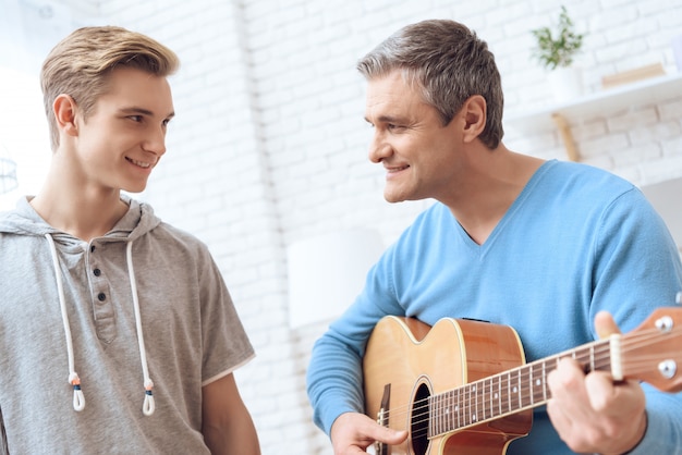 Vater spielt mit seinem Sohn Gitarre.