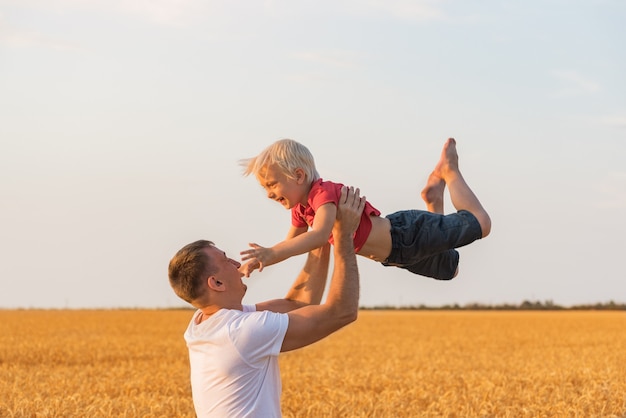 Vater spielt mit Sohn draußen im Feld