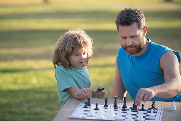 Vater spielt Schach mit der Sohnfamilie außerhalb von Spielspielen und Aktivitäten für Kinder