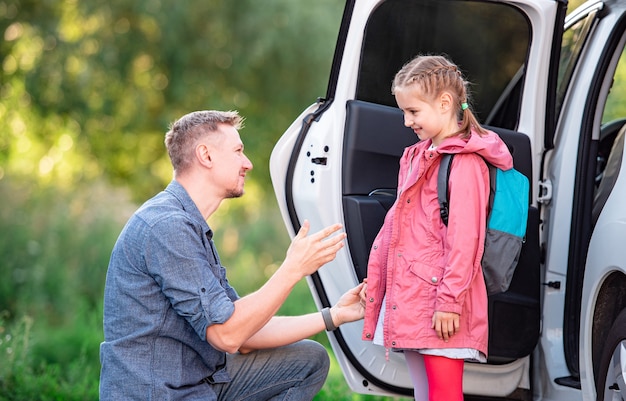 Vater trifft kleines Schulmädchen nach dem Unterricht auf dem Parkplatz