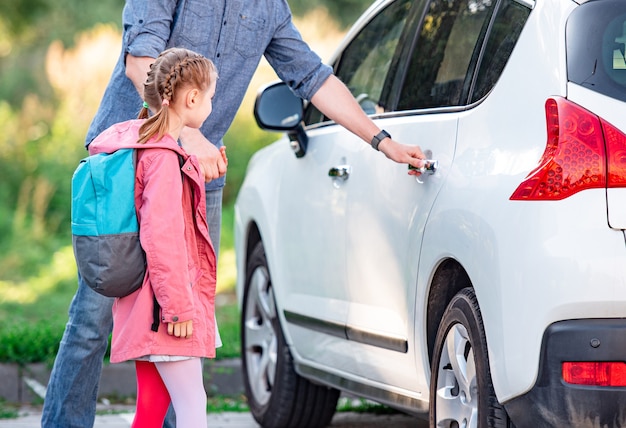 Vater trifft Tochter nach der Schule und öffnet die Autotür