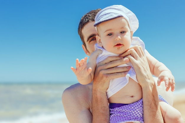 Vater umarmt den kleinen Sohn am Strand.