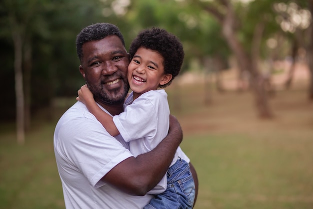 Vater und Afro-Sohn, die sich im Park halten. Vatertag.