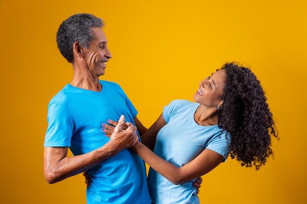 Vater und Afro-Tochter, die auf gelbem Hintergrund lächeln. Vatertagskonzept