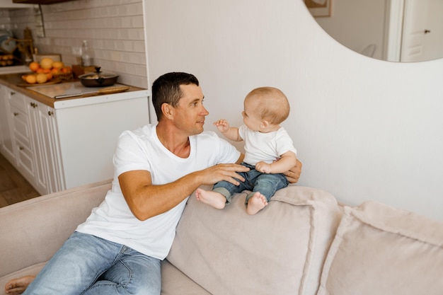 vater und baby auf der couch spielen zu hause