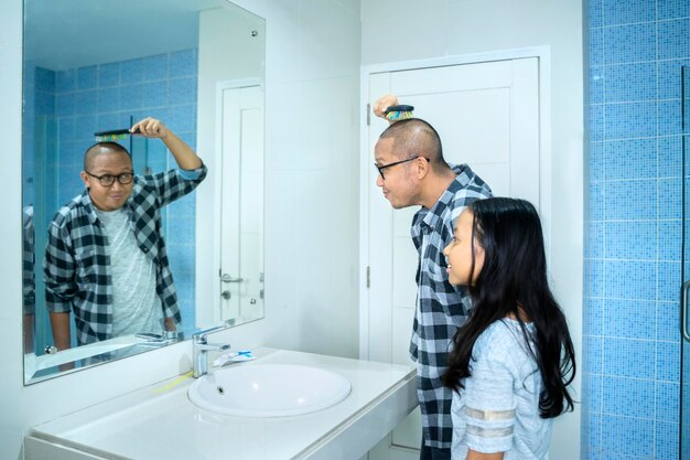 Vater und Kind kämmen sich vor dem Spiegel die Haare