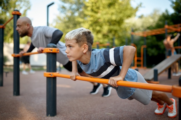 Vater und Kind machen Sport, Sporttraining auf dem Spielplatz im Freien. Die Familie führt einen gesunden Lebensstil, Fitnesstraining im Sommerpark