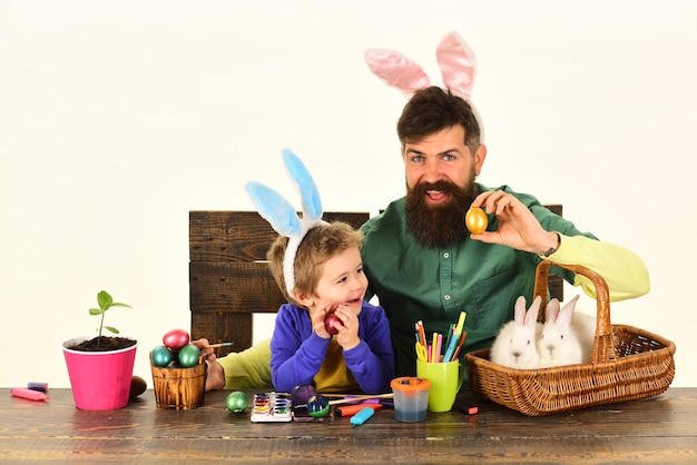 Vater und Kind malen Ostereier Hasenohren Konzept Kind mit Korb mit bemalten Eiern