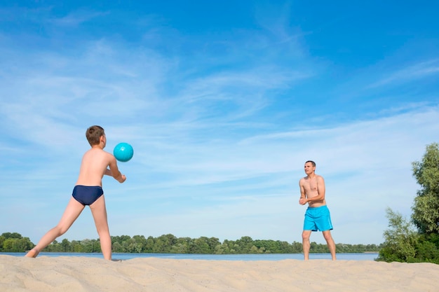 Vater und Kind spielen Beachvolleyball aktiven Lebensstil