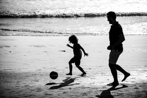 Vater und Kind spielen Outdoor-Silhouette bei Sonnenuntergang Vater und Sohn spielen Fußball oder Fußball auf der Be