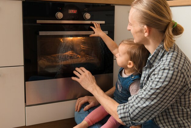 Vater und Kind warten auf frisch gebackene Brötchen in der Nähe des Ofens