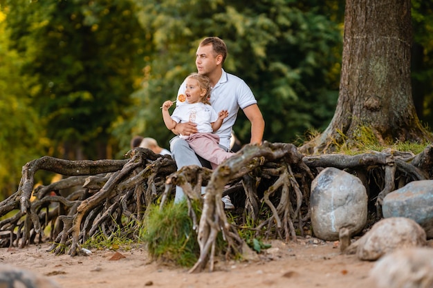 Vater und kleine süße Tochter zusammen im Sommer in der Natur ein kleines Mädchen isst einen Lutscher