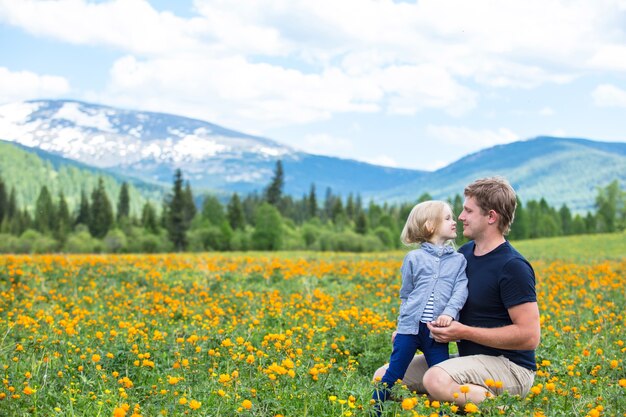 Vater und kleine Tochter Familie schön und glücklich, im Sommer zusammen auf der Wiese gegen die Berge mit Schnee lächelnd