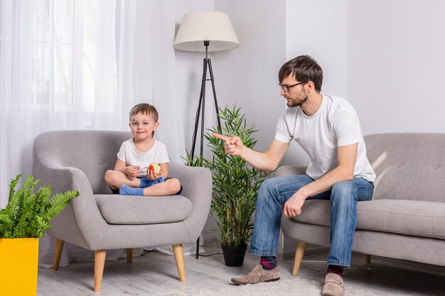 Vater und kleiner Sohn besprechen etwas Ernstes im Wohnzimmer zu Hause Familie des Vertrauens