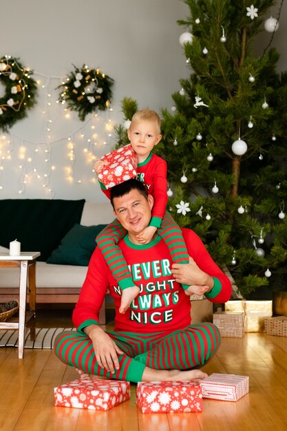 Vater und kleiner Sohn im kuscheligen Pyjama beim Auspacken von Geschenken