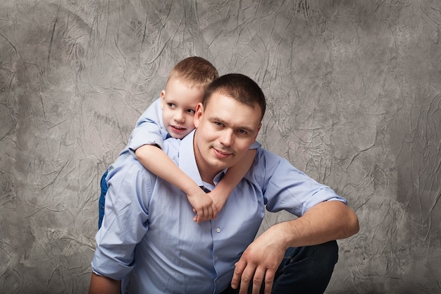 Vater und kleiner Sohn in blauen Hemden vor grau strukturiert