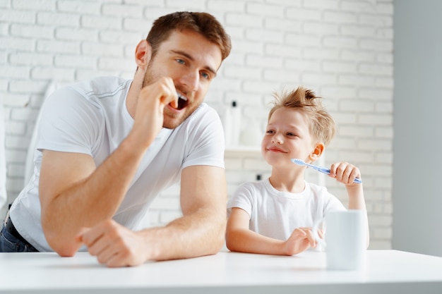 Vater und kleiner Sohn putzen gemeinsam die Zähne im Badezimmer