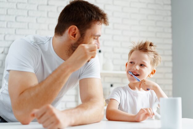 Vater und kleiner Sohn putzen gemeinsam die Zähne im Badezimmer