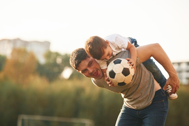 Vater und kleiner Sohn spielen und amüsieren sich im Freien mit einem Profifußball