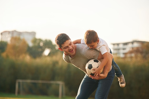 Vater und kleiner Sohn spielen und amüsieren sich im Freien mit einem Profifußball