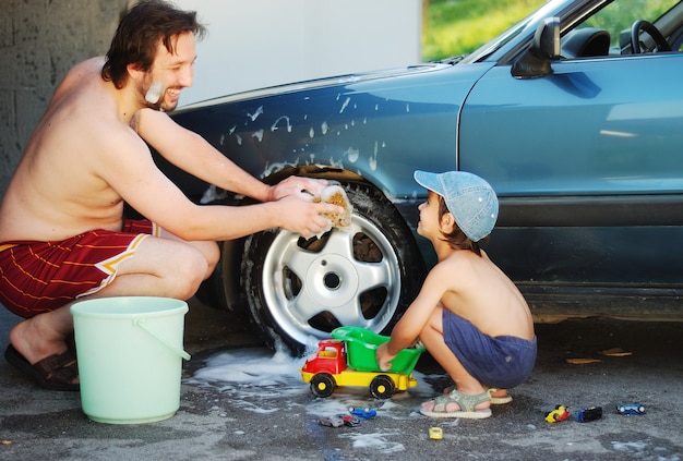 Vater und kleiner Sohn spielen und waschen Auto