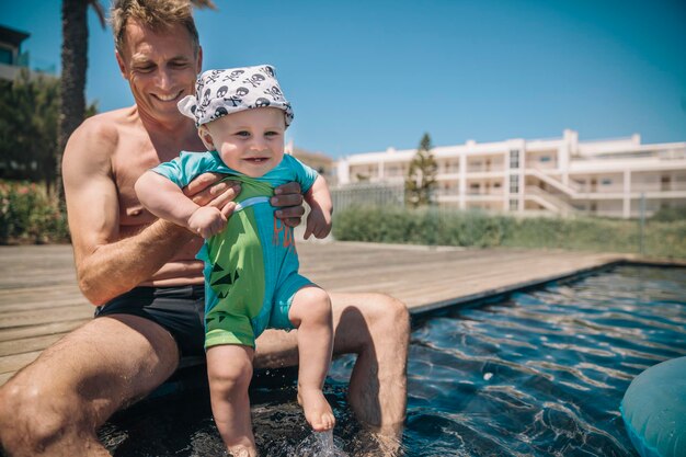 Vater und kleiner Sohn testen während der Sommerferien Wasser im Schwimmbad