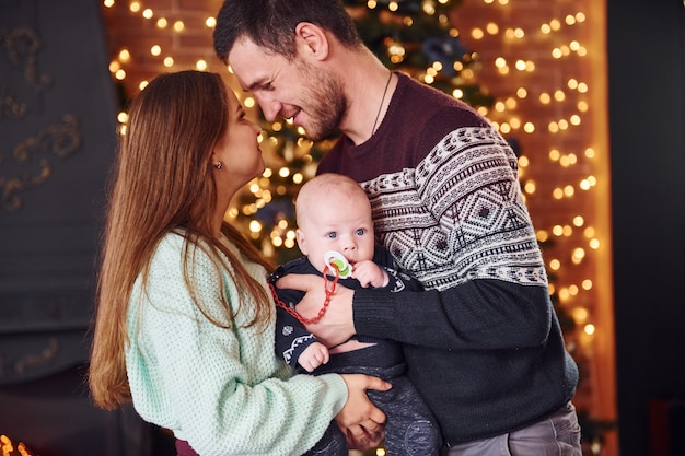 Vater und Mutter mit ihrem Kind zusammen im weihnachtlich dekorierten Raum.