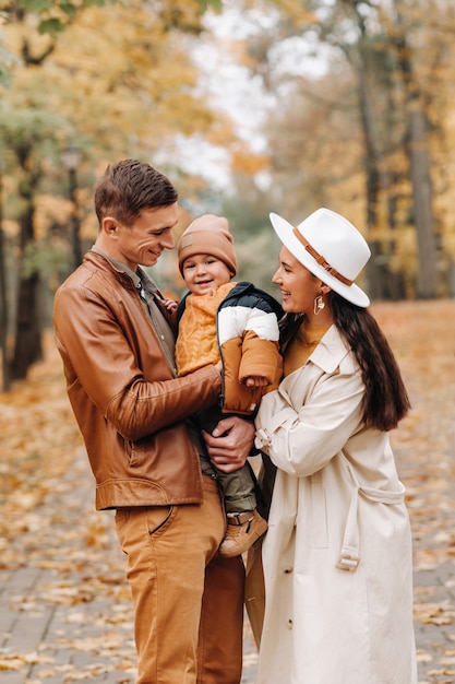 Vater und Mutter mit Sohn gehen im Herbstpark. Eine Familie geht im goldenen Herbst in einem Naturpark spazieren.