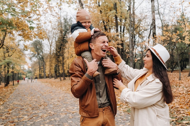 Vater und Mutter mit Sohn gehen im Herbstpark. Eine Familie geht im Goldenen Herbst in einem Naturpark spazieren.