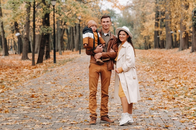 Vater und Mutter mit Sohn wandern im Herbstpark walking