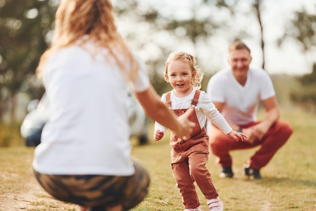 Foto vater und mutter verbringen das wochenende im freien in der nähe des waldes mit tochter