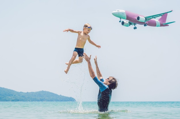 Vater und Sohn amüsieren sich am Strand und beobachten die landenden Flugzeuge. Reisen in einem Flugzeug mit Kinderkonzept.