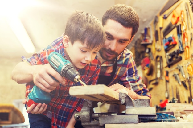 Vater und Sohn arbeiten mit Bohrmaschine in der Werkstatt