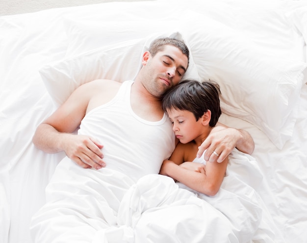 Vater und Sohn auf dem Bett liegen und schlafen