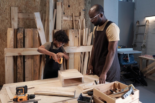 Vater und Sohn bauen Vogelhäuschen in der Werkstatt