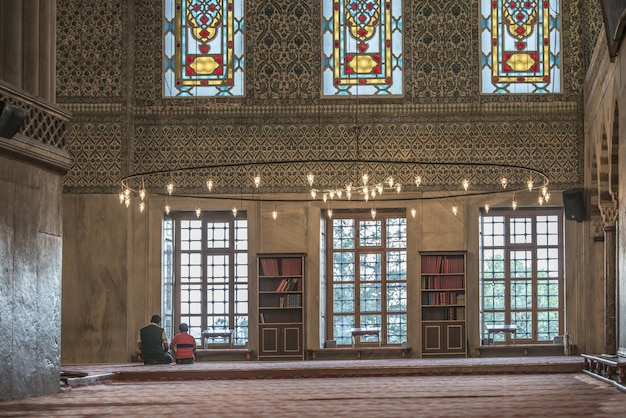 Vater und Sohn beten an der Wand mit großen Fenstern in der Blauen Moschee