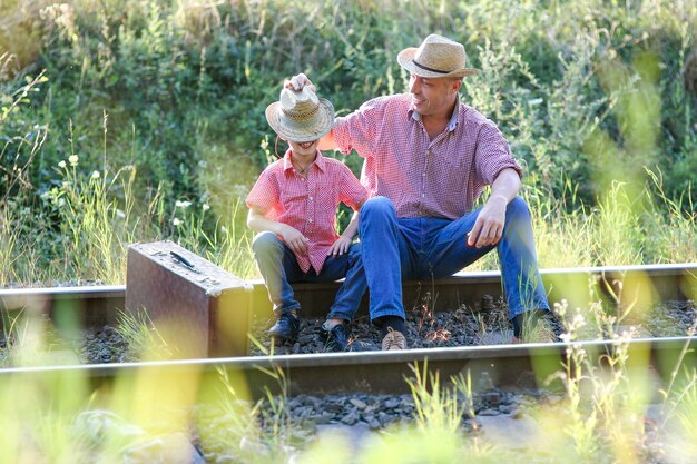 Vater und Sohn Cowboys Konzept Glück zusammen in der Nähe von Eisenbahn mit Koffer