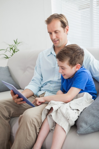 Vater und Sohn, der Tabletten-PC auf der Couch verwendet